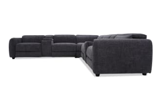 Dark gray fabric sectional sofa with plush cushions, wide armrests, and an integrated center console, designed for modern living rooms.