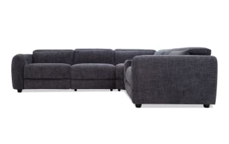 Dark gray fabric sectional sofa with plush cushions, rounded arms, and low black legs, designed for modern living room comfort.