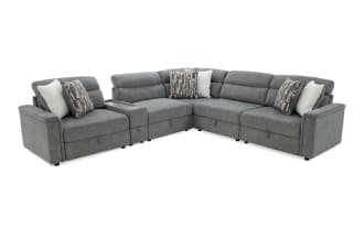 Gray fabric sectional sofa with plush cushions, patterned and solid throw pillows, and a built-in middle console, ideal for modern living rooms.