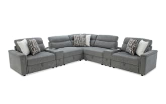 Gray fabric sectional sofa with plush cushions and patterned throw pillows, featuring a modern design and L-shaped configuration for spacious seating.
