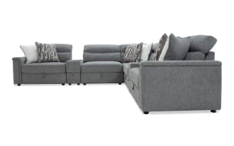 Gray fabric sectional sofa with plush cushions and patterned throw pillows, featuring a modern design and L-shaped configuration for spacious seating.