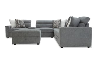 Gray fabric sectional sofa with adjustable headrests, matching ottoman, and patterned throw pillows, designed for modern living rooms.