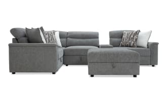 Gray fabric sectional sofa with adjustable headrests, patterned and white throw pillows, and a matching ottoman, ideal for modern living rooms.