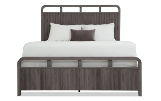 Modern queen bed frame in dark gray wood with vertical grooves, featuring a high headboard and low footboard, styled with white bedding and pillows.