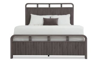 King-size bed with dark gray wood frame featuring vertical grooves, matching headboard and footboard, white bedding, and accent pillows.