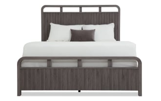 Modern bedroom set with dark gray wood finish, featuring a bed with slatted headboard and footboard, a two-drawer nightstand, and a six-drawer dresser with mirror.