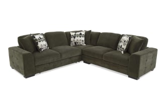 Dark olive green sectional sofa with plush cushions and three patterned throw pillows, featuring a modern design and fabric upholstery.