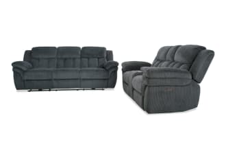 Dark gray fabric reclining sofa and loveseat set with plush padded armrests and backrests, featuring a textured upholstery and manual recline controls.