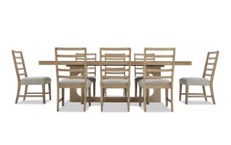 Solid wood rectangular dining table with a natural finish, paired with eight ladder-back chairs featuring beige cushioned seats and wooden frames.