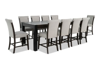 Aurora 11-piece transitional dining set with extendable brown-black MDF and rubberwood table, gray polyester fabric stools with memory foam seats, and lift-top storage compartments.