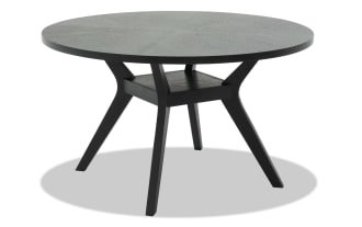 Round black wooden dining table with angled legs and a sturdy crossbar support, modern minimalist style for home or office.