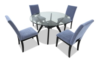 Dining set with four light blue upholstered chairs featuring black wooden legs and a glass-top table with black angled supports, modern style.