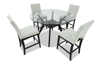 Modern dining set featuring a round glass table with black wooden legs and four upholstered beige fabric chairs with black wooden frames.