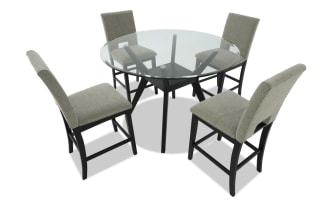 Modern dining set with four beige upholstered chairs featuring black wooden legs and a round glass tabletop with black angled wooden base, ideal for contemporary interiors.
