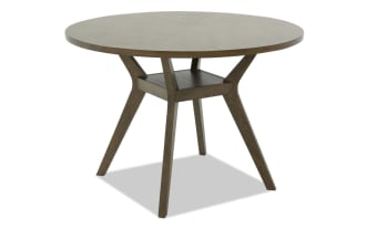 Wooden dining table with a round top and angled legs in a dark brown finish, showcasing a modern rustic design.