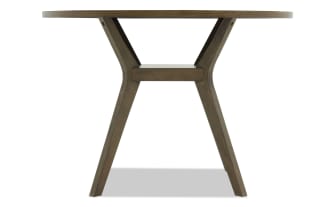 Wooden dining table with a round top and angled legs in a dark brown finish, showcasing a modern rustic design.
