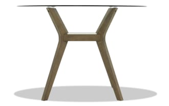Round dining table with clear glass top and angled wooden legs in a natural brown finish, modern minimalist style.