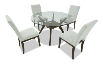 Dining set with four beige upholstered chairs featuring wooden legs and a rectangular glass-top table with wooden angled legs, modern style.