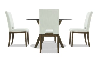 Dining set with four beige upholstered chairs featuring wooden legs and a rectangular glass-top table with wooden angled legs, modern style.