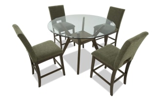 Round glass-top dining table with dark wood base and four olive green upholstered chairs, featuring cushioned seats and backs.