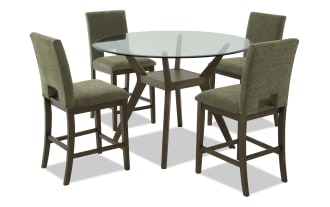 Round glass-top dining table with dark wood base and four olive green upholstered chairs, featuring cushioned seats and backs.