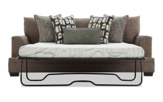 Brown fabric sofa bed with a black metal frame mattress support, featuring six decorative pillows in geometric and textured patterns, ideal for small living spaces.
