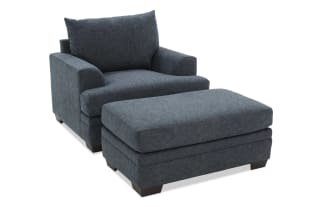 Dark gray upholstered armchair with plush cushions, wide seat, and low wooden legs, ideal for modern living room seating.