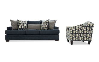 Dark blue fabric sofa with plush cushions and patterned throw pillows, paired with a modern armchair featuring a geometric multicolor fabric design and dark wooden legs.