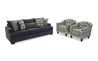 Dark blue fabric sofa with six patterned and textured throw pillows, paired with two matching armchairs featuring geometric multicolor upholstery and dark wooden legs.