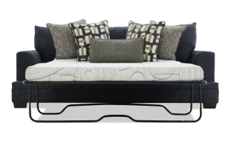 Dark gray fabric sofa bed with metal frame pull-out mattress, featuring six decorative patterned and textured throw pillows for added comfort and style.