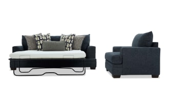 Dark gray fabric sofa bed with metal frame pull-out mattress, featuring multiple patterned and textured cushions, shown from front and side views.