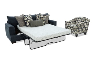Dark blue fabric sofa bed with metal frame pull-out mattress, accompanied by a patterned armchair with geometric beige, brown, and green upholstery.