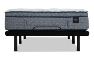 Mattress labeled "ENVY WELCOME TO BED" with a thick, quilted, gray fabric and white top, placed on a black metal bed frame with sturdy legs.