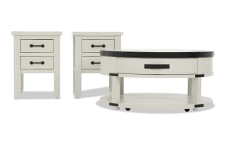 Set of white wooden furniture including two square side tables with black metal handles and one round coffee table with a black metal rim and lower shelf, featuring a rustic farmhouse style.