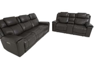Dark gray leather reclining three-seat sofa with padded headrests, armrests, and visible control buttons on the side for adjustable comfort.