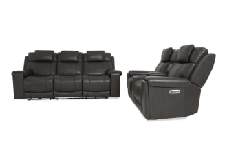 Dark gray leather reclining three-seat sofa with padded headrests, armrests, and visible control buttons on the side for adjustable comfort.