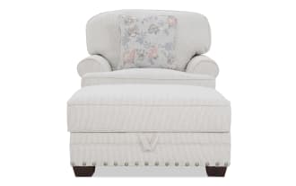 Beige striped fabric chaise lounge chair with rolled arms, cushioned back, floral accent pillow, and nailhead trim on wooden legs.