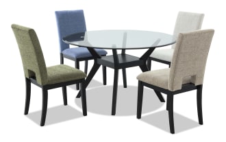 Round glass dining table with black wooden legs, accompanied by four upholstered chairs in blue, beige, light gray, and olive green fabric.