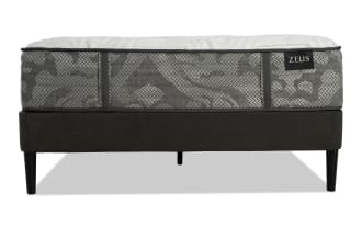 Zeus mattress with gray patterned fabric and white quilted top on a black upholstered bed frame with tapered legs, modern design.