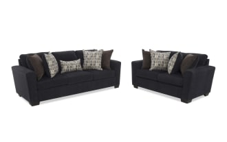 Dark charcoal fabric sofa with three seat cushions, flared arms, and six decorative pillows in patterned and solid brown tones, shown from front and side angles.