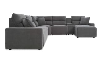 Large modern gray fabric sectional sofa with plush cushions, L-shaped design, and built-in armrest storage compartment, ideal for spacious living rooms.