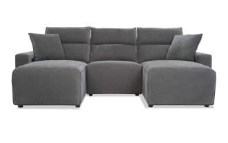Modern gray fabric sectional sofa with chaise lounges on both ends, plush cushions, and a minimalist design for living room seating.