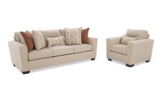 Beige fabric sofa set with three-seat couch and armchair, featuring plush cushions and decorative brown and patterned throw pillows, modern design.
