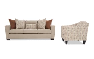 Beige fabric sofa with dark wooden legs, featuring three seat cushions and five decorative pillows in brown and patterned beige tones, paired with a matching patterned beige armchair with dark wooden legs.
