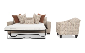 Beige fabric sofa bed with metal frame mattress support, adorned with patterned and solid rust-colored throw pillows, next to a beige and rust patterned armchair with dark wooden legs.