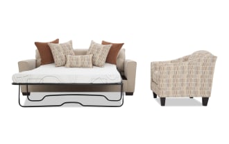 Beige fabric sofa bed with metal frame mattress pull-out, accompanied by a patterned beige and brown accent chair, both with wooden legs and decorative cushions.
