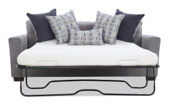 Gray fabric sofa bed with metal frame pull-out mattress, featuring white mattress and six decorative pillows in blue and gray patterns, modern style.