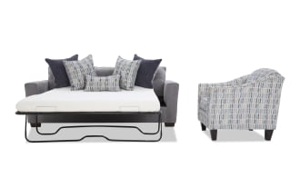 Gray fabric sofa bed with metal frame pull-out mattress and five decorative pillows, next to a patterned blue and gray upholstered armchair.