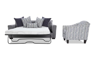 Gray fabric sofa bed with metal frame mattress pulled out, adorned with blue and patterned throw pillows, next to a blue patterned upholstered armchair with dark wooden legs.
