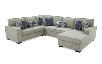Gray fabric sectional sofa with chaise lounge, featuring multiple blue and patterned throw pillows, modern design with clean lines and black legs.